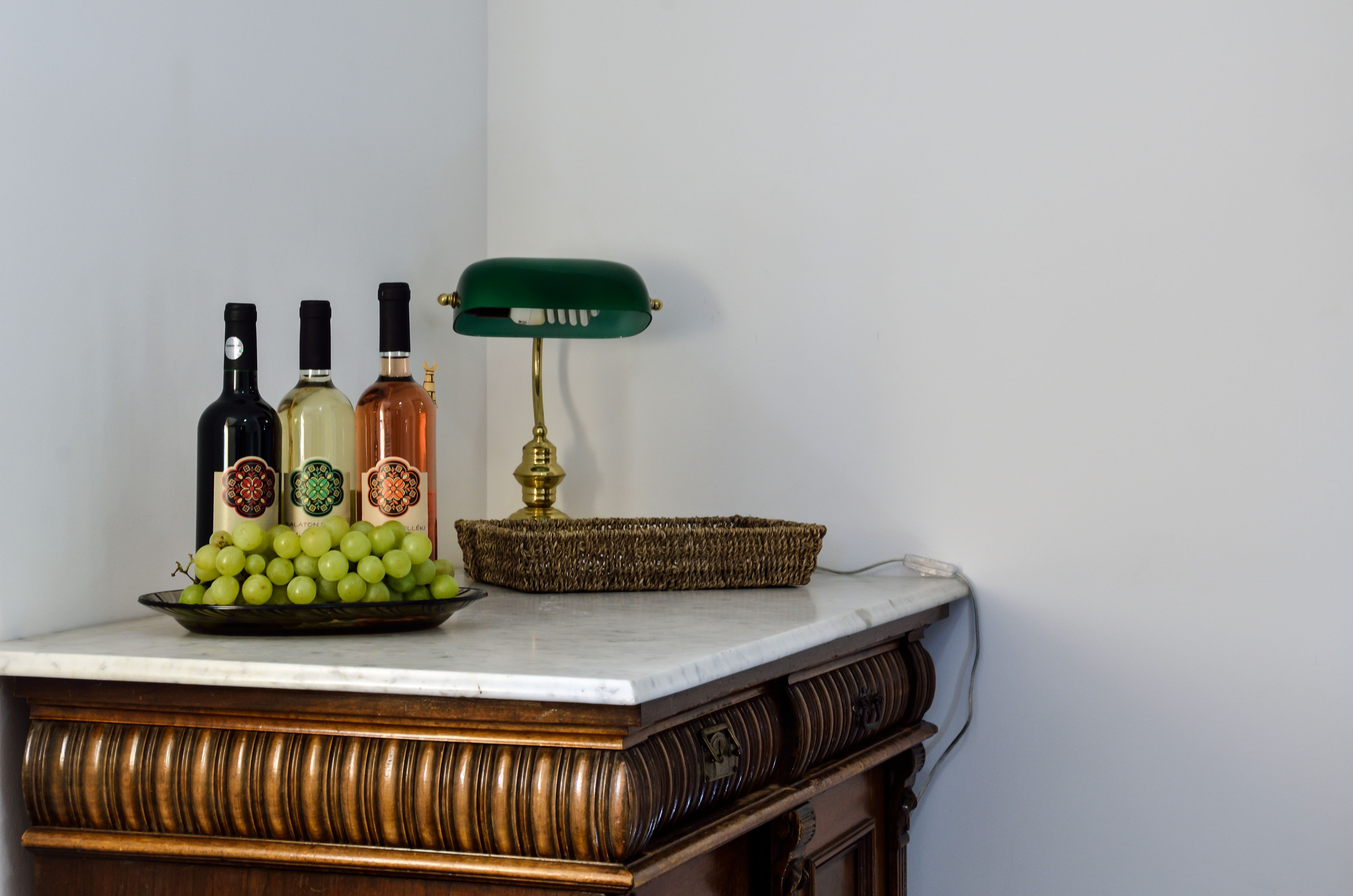 Antik komód borokkal és bankárlámpával