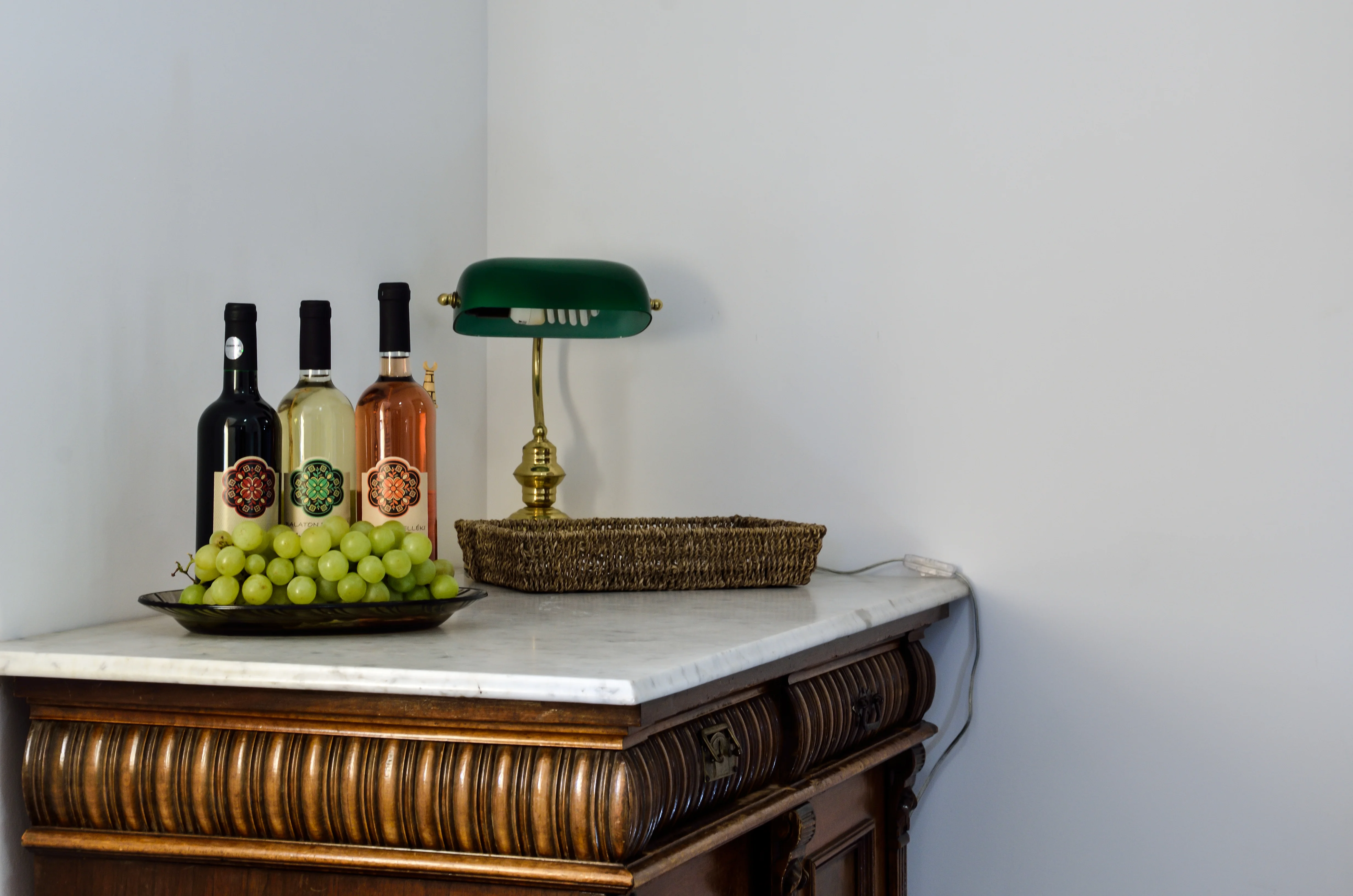 Antik komód borokkal és bankárlámpával